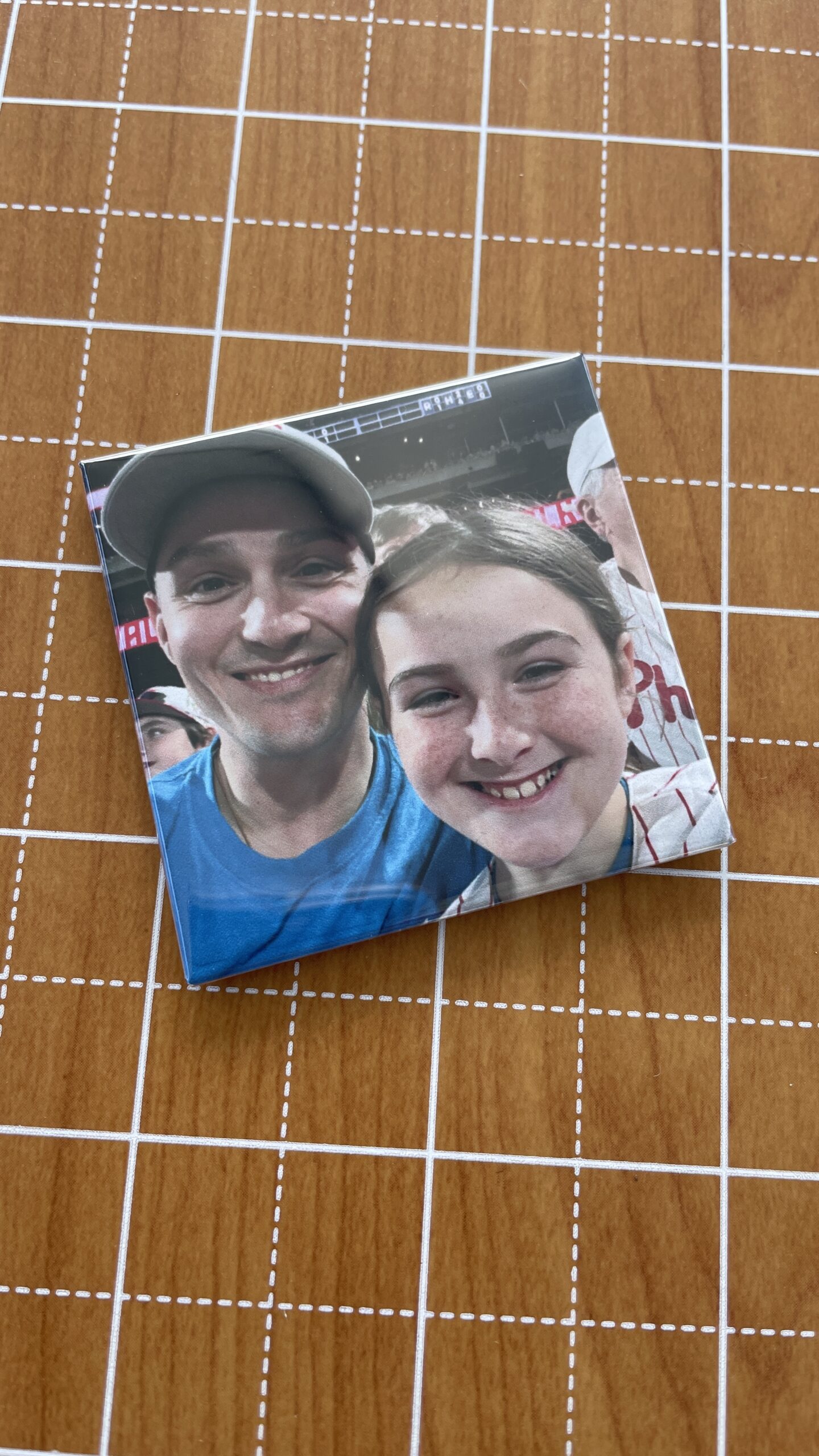 A happy father and daughter pose for a selfie at a baseball game, both smiling widely. The photo captures their joyful moment at a sporting event.