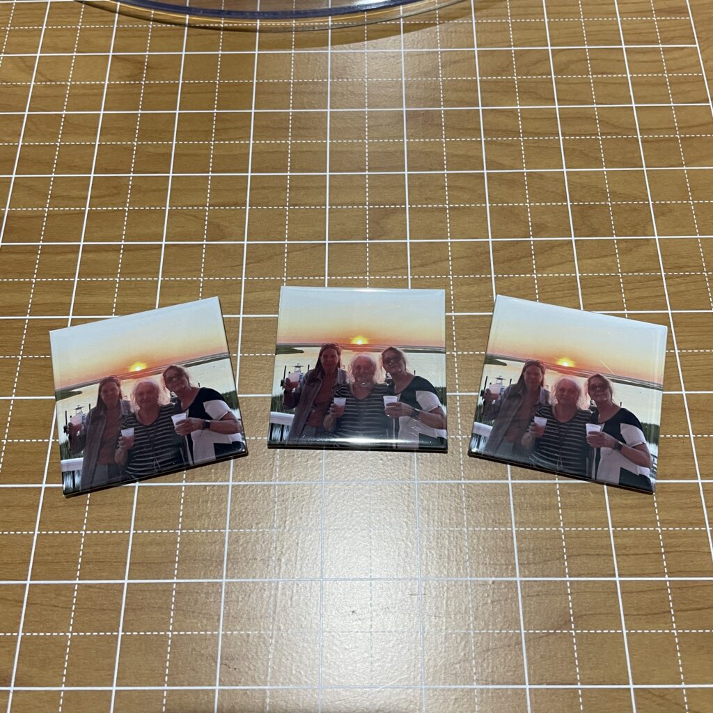 Three printed photos featuring two women and an elderly man holding drinks, posed against a sunset backdrop by a body of water.